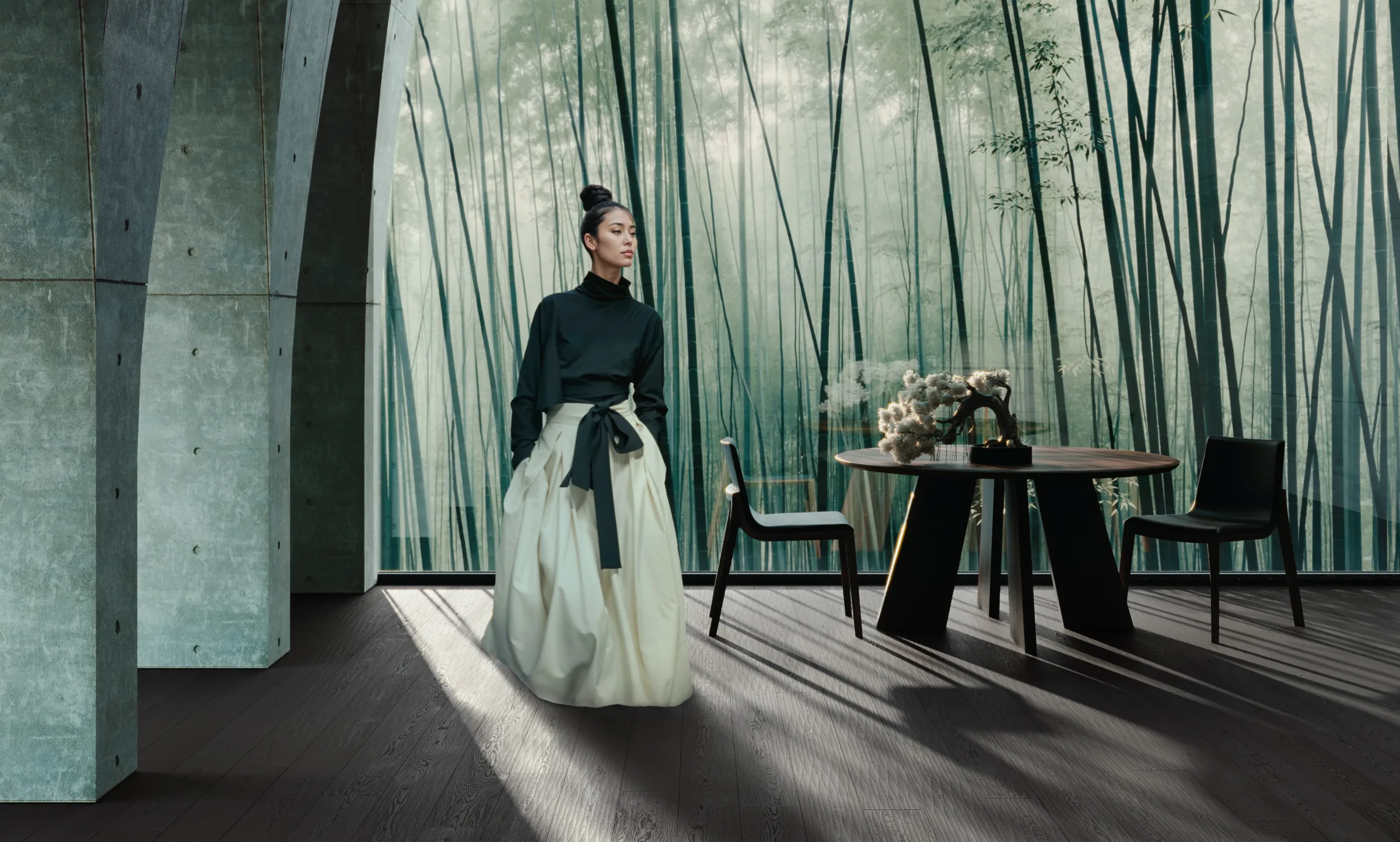 A woman stands beside a sculptural dining table in a bamboo-lined interior.