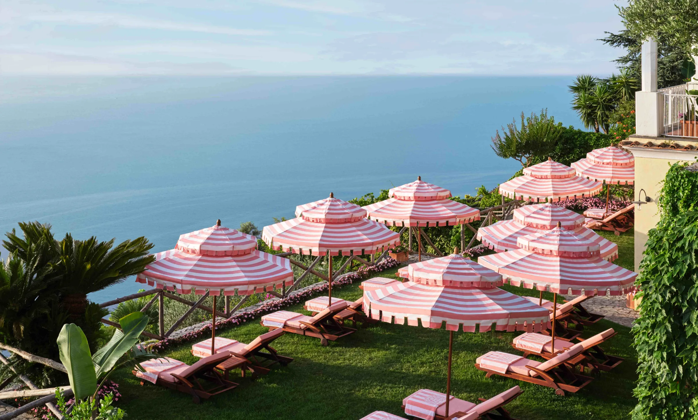 Rows of striped umbrellas overlooking a Mediterranean coastline.