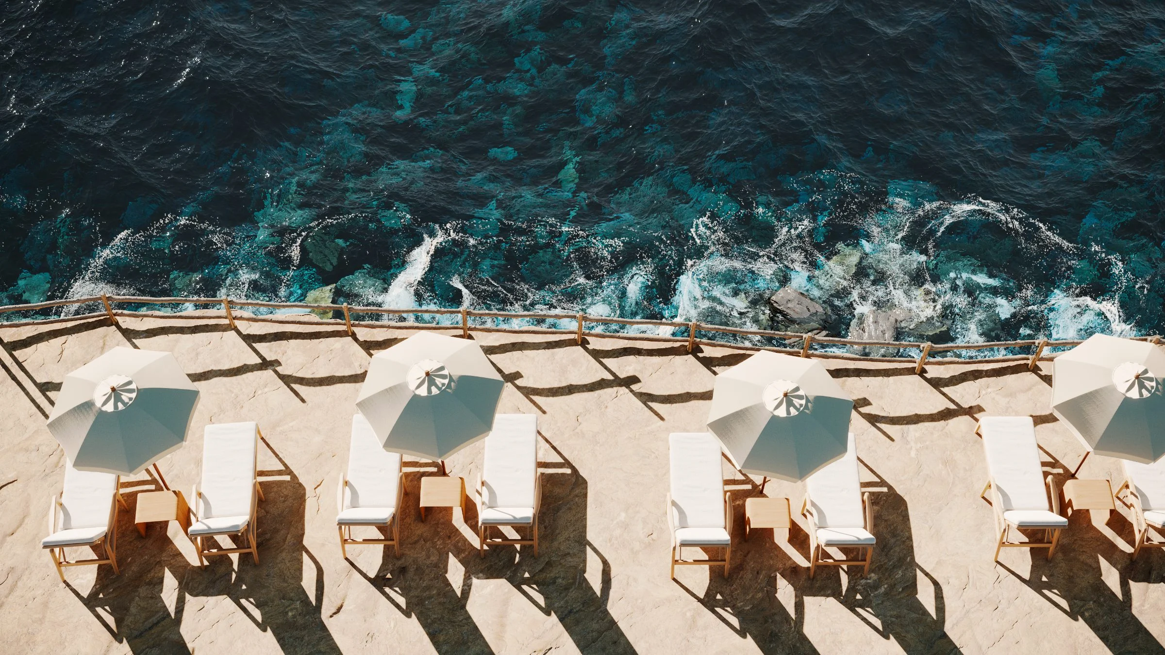 Sunlit parasols and loungers on a coastal terrace above the sea.